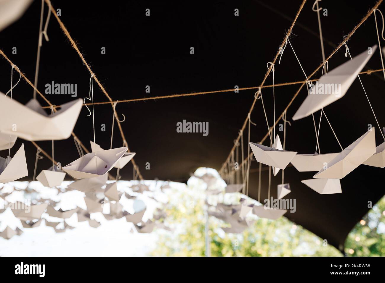 Un primo piano di molte barche di carta appese al soffitto del padiglione nel parco Foto Stock