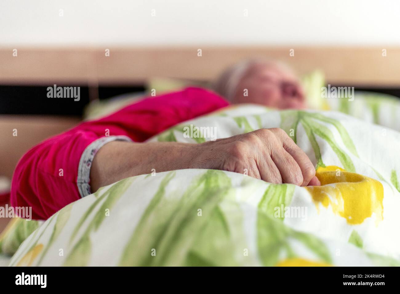 Mano rugosa di vecchia donna sdraiata a letto. Paziente anziano Foto Stock