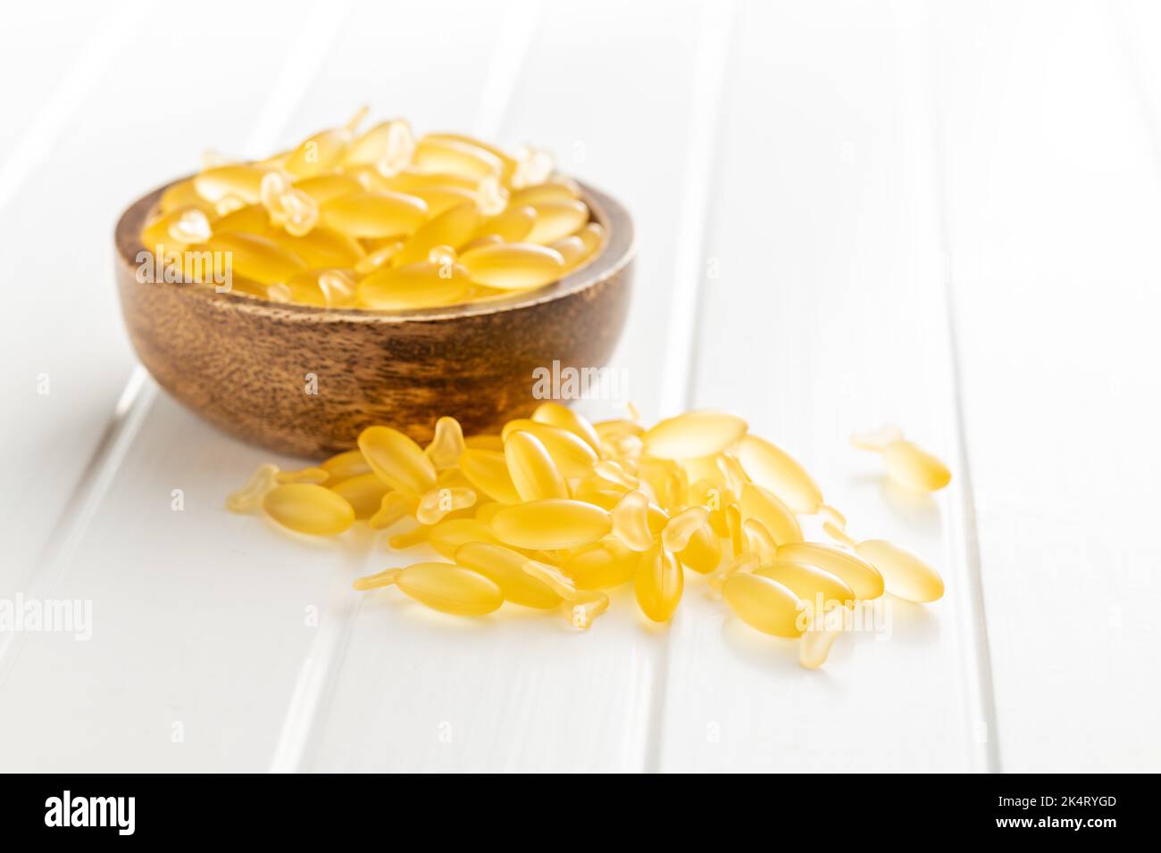 Capsule di olio di pesce. Omega 3 pillole gialle in ciotola sul tavolo bianco. Foto Stock