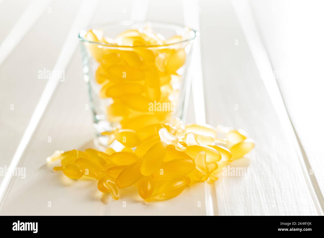 Capsule di olio di pesce. Giallo omega 3 pillole in vetro sulla tavola bianca. Foto Stock