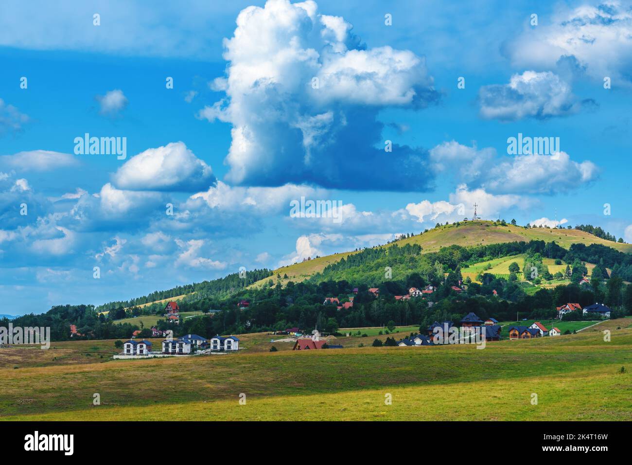 Bellissimo paesaggio pittoresco della regione di Zlatibor con case in stile architettonico distintivo sparse sulle verdi colline nelle soleggiate giornate estive Foto Stock