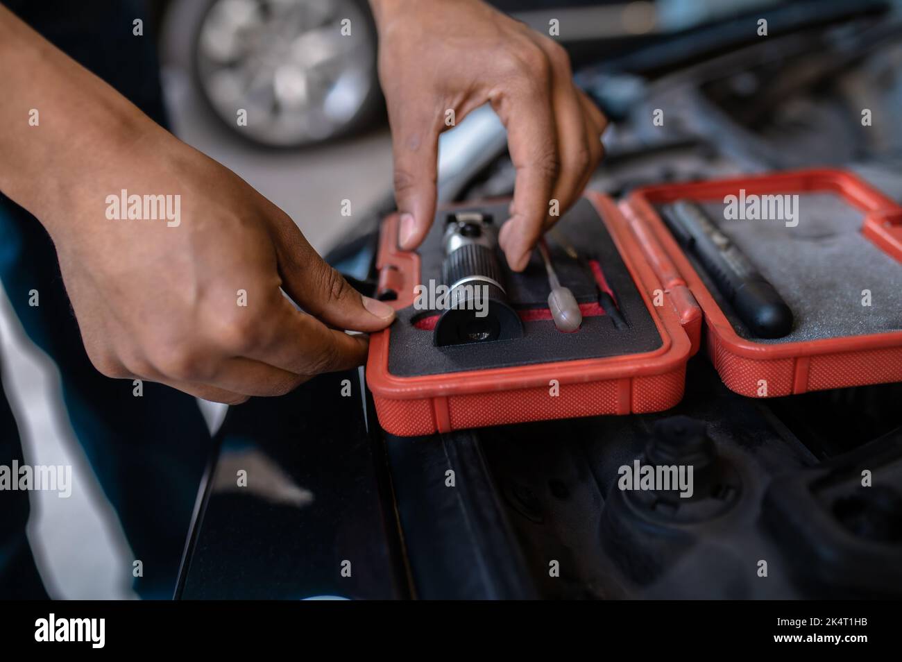 Operaio esperto della stazione di servizio dell'automobile che sceglie un dispositivo ottico Foto Stock