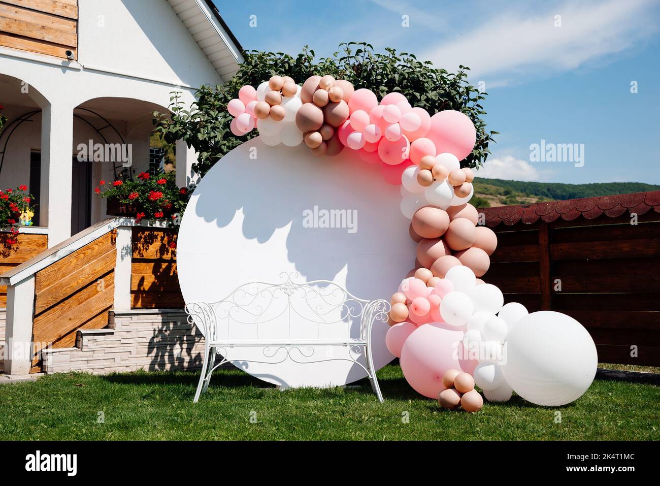 Uno striscione con palloncini rosa e bianchi in giardino per una