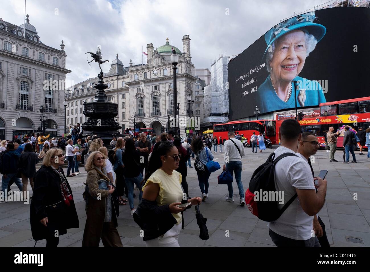 Con la pubblicità sospesa, i visitatori e i turisti a Piccadilly Circus interagiscono sotto un'immagine a colori della Regina Elisabetta II che è in mostra sugli schermi pubblicitari su larga scala il giorno successivo alla sua morte, il 9th settembre 2022 a Londra, Regno Unito. La regina, che aveva 96 anni, regnò come monarca del Regno Unito e del Commonwealth per 70 anni. Foto Stock