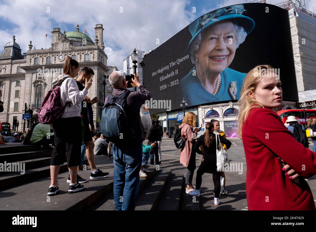 Con la pubblicità sospesa, i visitatori e i turisti a Piccadilly Circus interagiscono sotto un'immagine a colori della Regina Elisabetta II che è in mostra sugli schermi pubblicitari su larga scala il giorno successivo alla sua morte, il 9th settembre 2022 a Londra, Regno Unito. La regina, che aveva 96 anni, regnò come monarca del Regno Unito e del Commonwealth per 70 anni. Foto Stock