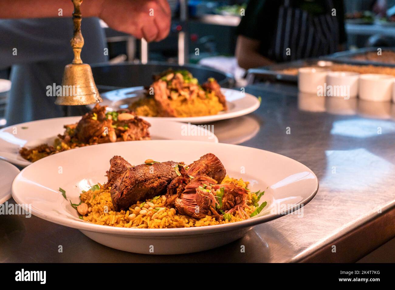 Piatti di cibo Kabseh al pass in attesa di essere raccolti da volontari e serviti in una festa mediorientale a sostegno del Falmouth e Penryn Wel Foto Stock