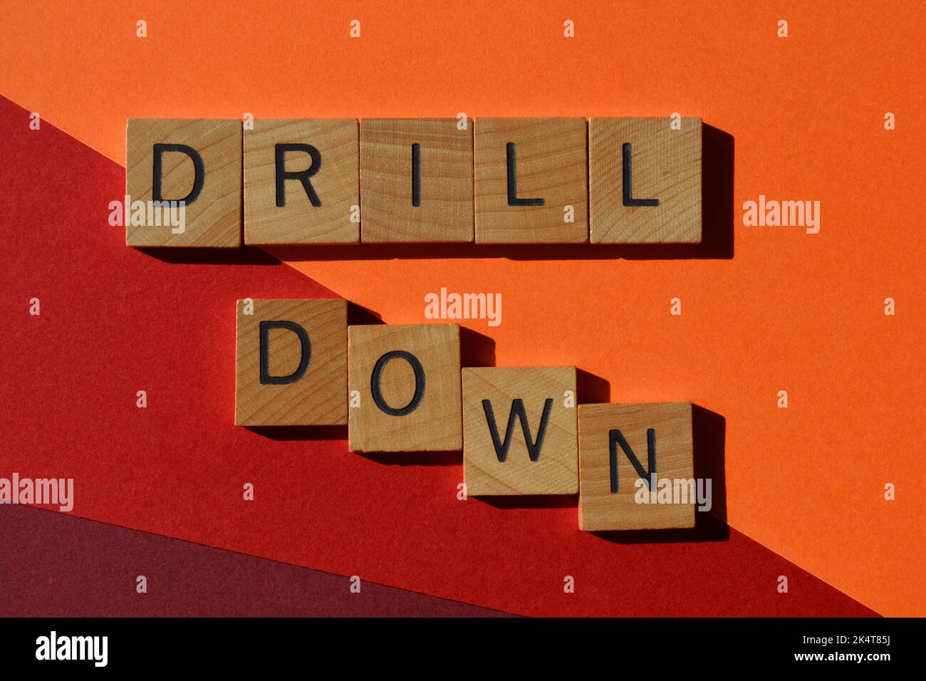 Drill-down, parole in lettere alfabetiche di legno isolate sullo sfondo, parola di buzzword che significa indagare o ricercare qualcosa di più, a un livello più profondo Foto Stock