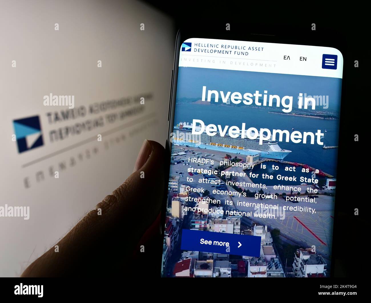 Persona che tiene il cellulare con il sito web della Repubblica ellenica Asset Development Fund (HRADF) sullo schermo con il logo. Messa a fuoco al centro del display del telefono. Foto Stock