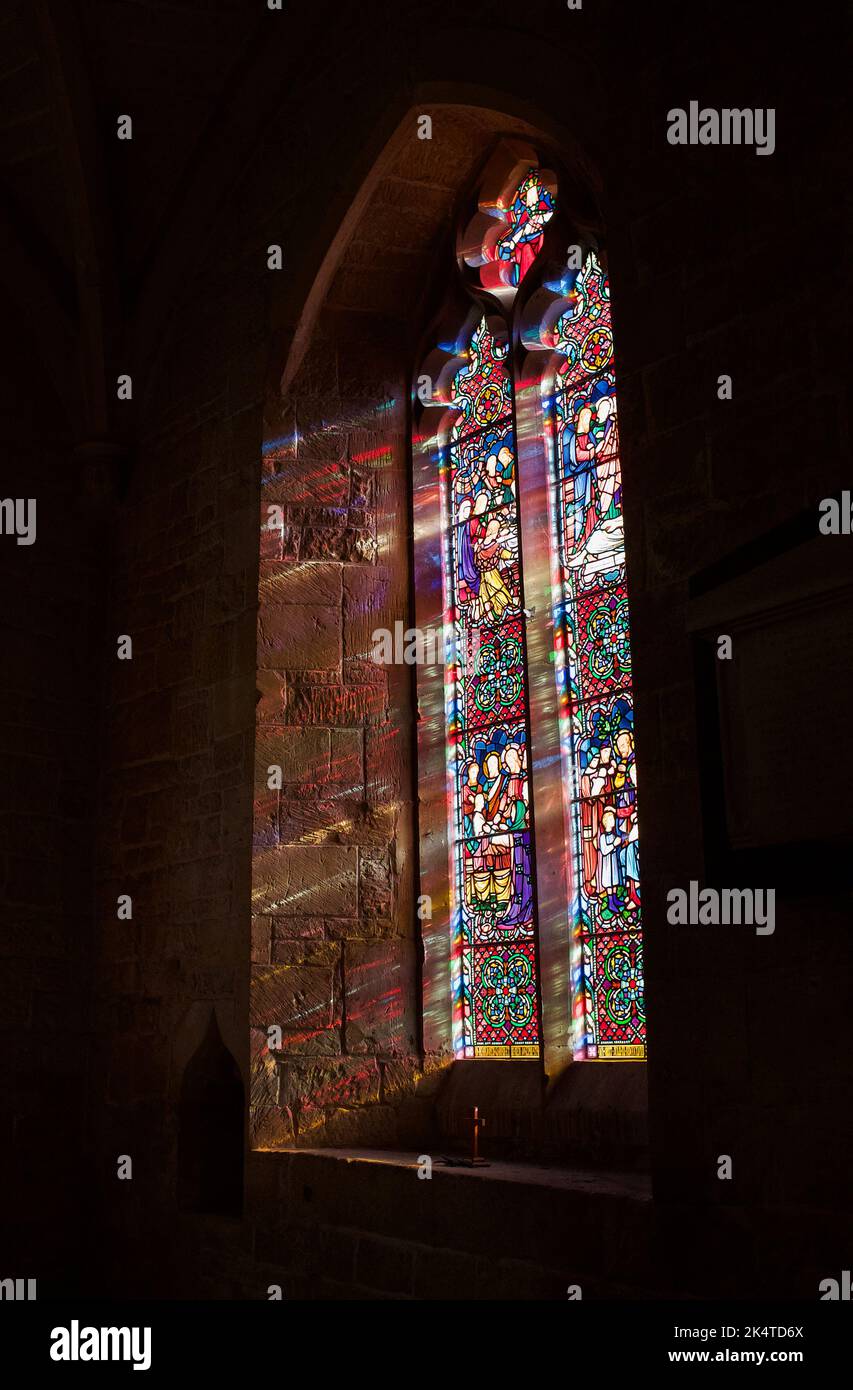 Luce del sole che arriva attraverso una finestra di vetro colorato presso la chiesa di St Peter's CoFe, Leckhampton, Cheltenham, Gloucestershire Foto Stock