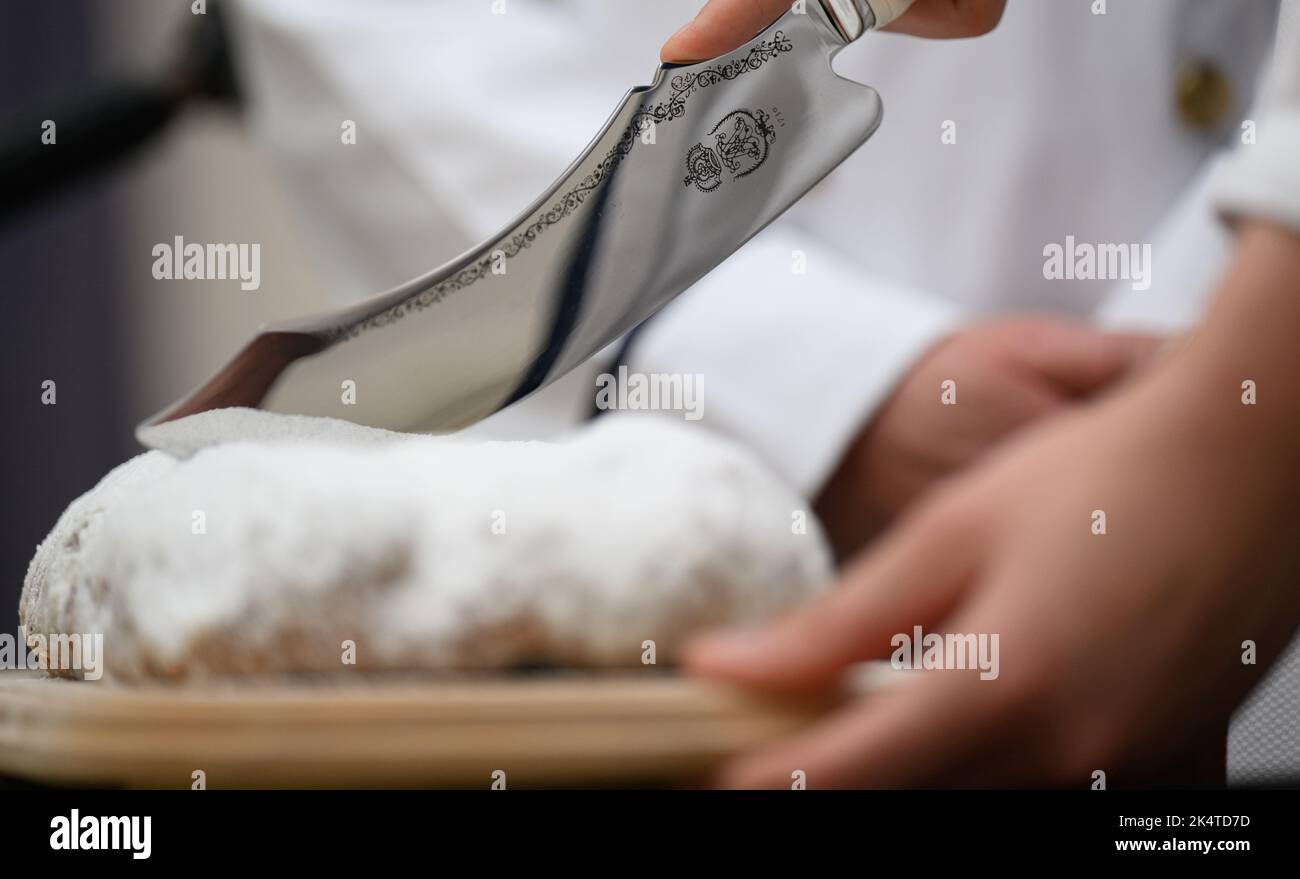 Dresda, Germania. 04th Ott 2022. Un coltello Stollen viene utilizzato per tagliare uno Stollen durante la presentazione della Stollen Girl di Dresda del 28th al Museo dei Trasporti. Il pasticciere tirocinante di 17 anni è l'ambasciatore dello Stollen di Natale di Dresda per la durata di un anno per conto dei fornai di Stollen di Dresda. Credit: Robert Michael/dpa/Alamy Live News Foto Stock