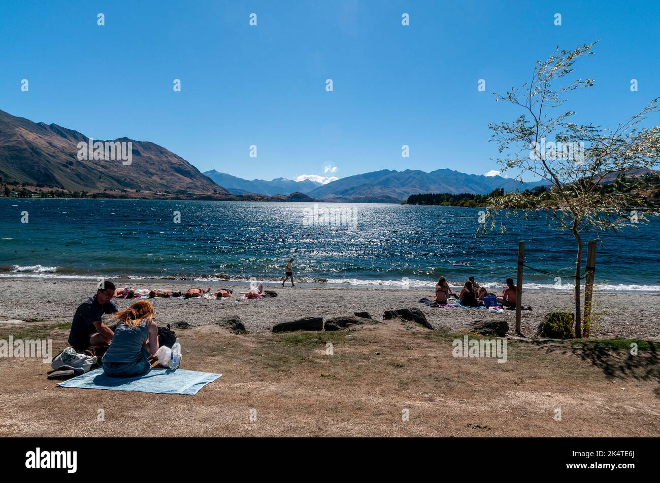 Prendere il sole sulla spiaggia sabbiosa del lago Wanaka, che copre un'area di 278 metri sul livello del mare e che è più di 300 metri di profondità. È il quarto-l della Nuova Zelanda Foto Stock