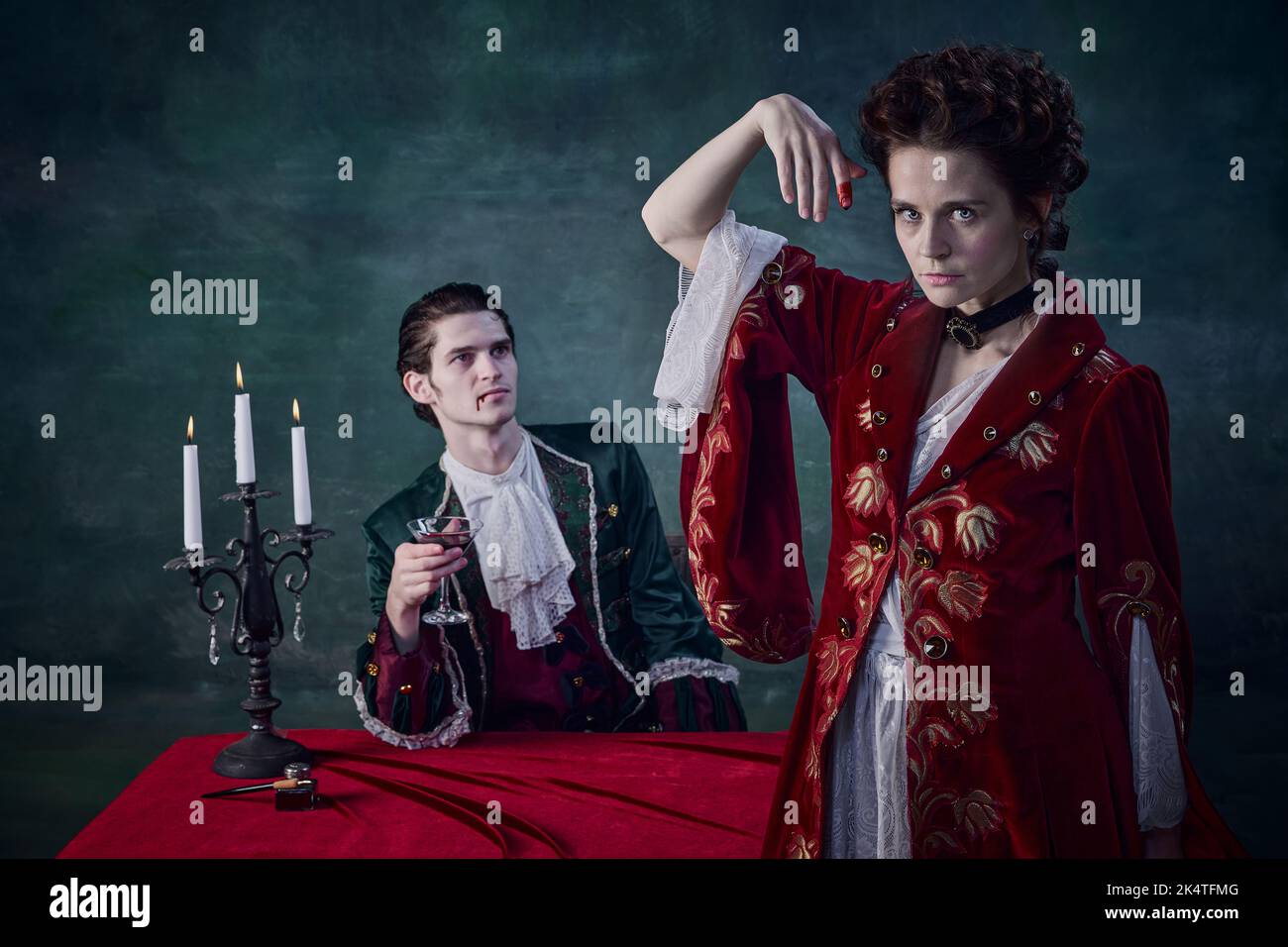 Ritratto di uomo e donna a immagine di vampiri medievali che bevono sangue di notte su sfondo verde scuro Foto Stock