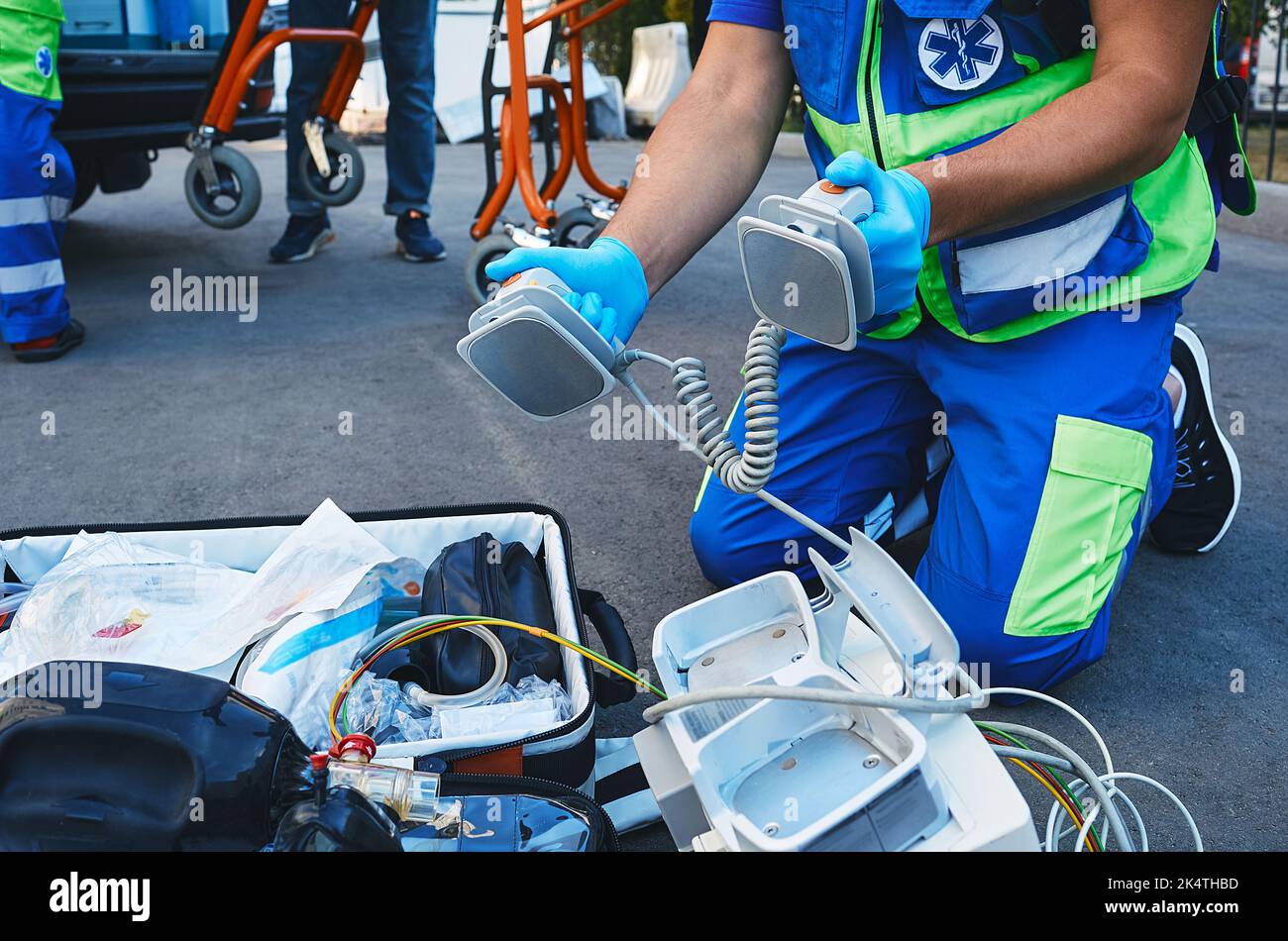 Ambulanza paramedica tenere gli elettrodi del defibrillatore nelle mani durante la rianimazione di un incidente all'aperto vicino all'ambulanza. Esecuzione del primo soccorso Foto Stock