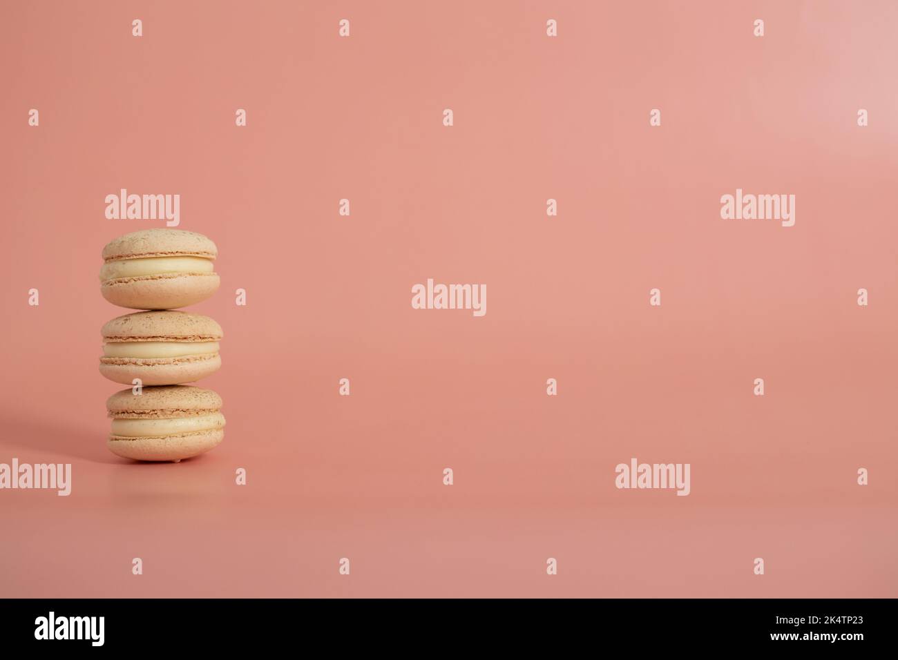 Macaroni dolci tondi su sfondo rosa. Vita morta con dolci di maccheroni e fiori diversi. Spazio di copia. Banner Foto Stock