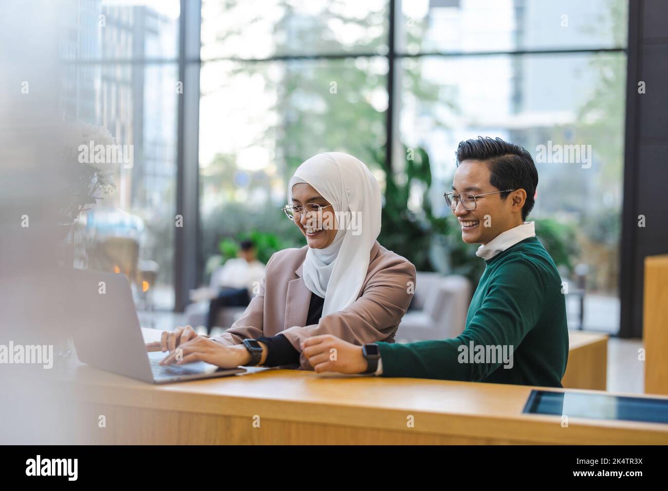 Giovane coppia di business utilizzando computer portatile in ufficio Foto Stock