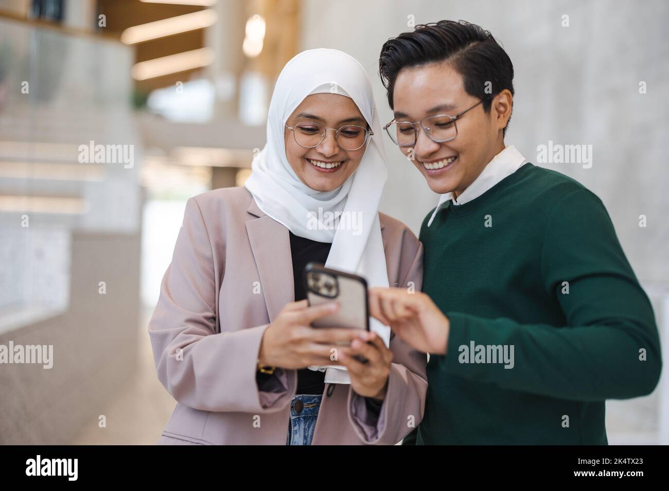 Sorridere una giovane coppia di lavoro che utilizza lo smartphone insieme Foto Stock