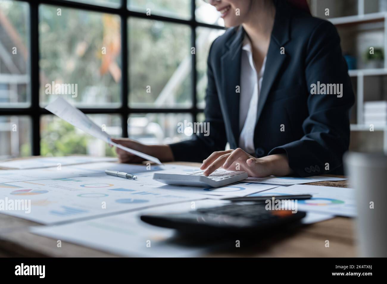 Asian Business Woman o contabile fanno matematica e analizzano con calcolatrice e documentazione su scrivania, conto, revisione e concetto di salvataggio Foto Stock