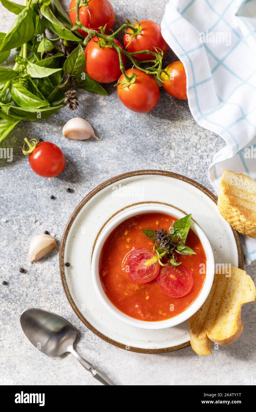 Zuppa vegana pomodori purè. Dieta sana vegetariana. Ciotola di zuppa di crema di pomodoro con basilico e crostini su un tavolo di pietra. Vista dall'alto. Foto Stock