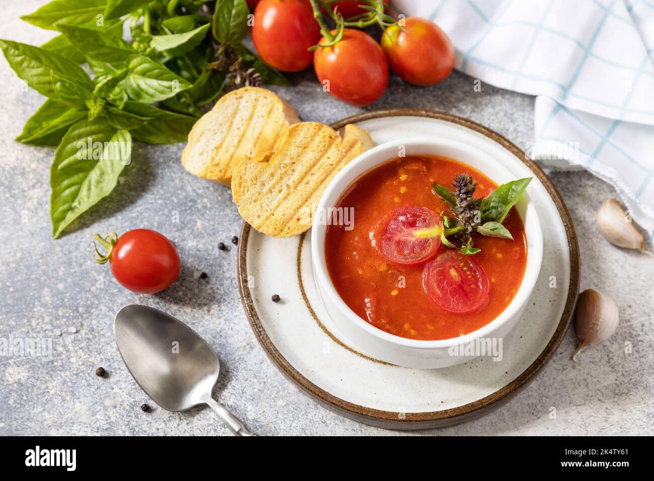 Zuppa vegana pomodori purè. Dieta sana vegetariana. Ciotola di zuppa di crema di pomodoro con basilico e crostini su un tavolo di pietra. Foto Stock