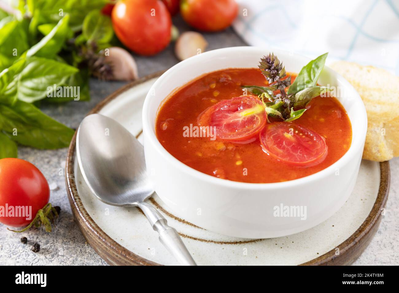 Dieta sana vegetariana. Zuppa vegana pomodori purè. Ciotola di zuppa di crema di pomodoro con basilico e crostini su un tavolo di pietra. Foto Stock