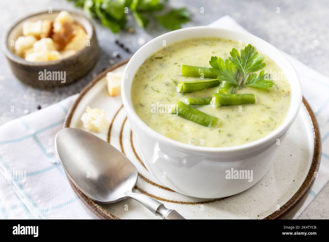 Purea di verdure verdi per zuppa vegana. Cibo sano. Ciotola di fagiolo verde e zuccini crema su un tavolo di pietra. Foto Stock