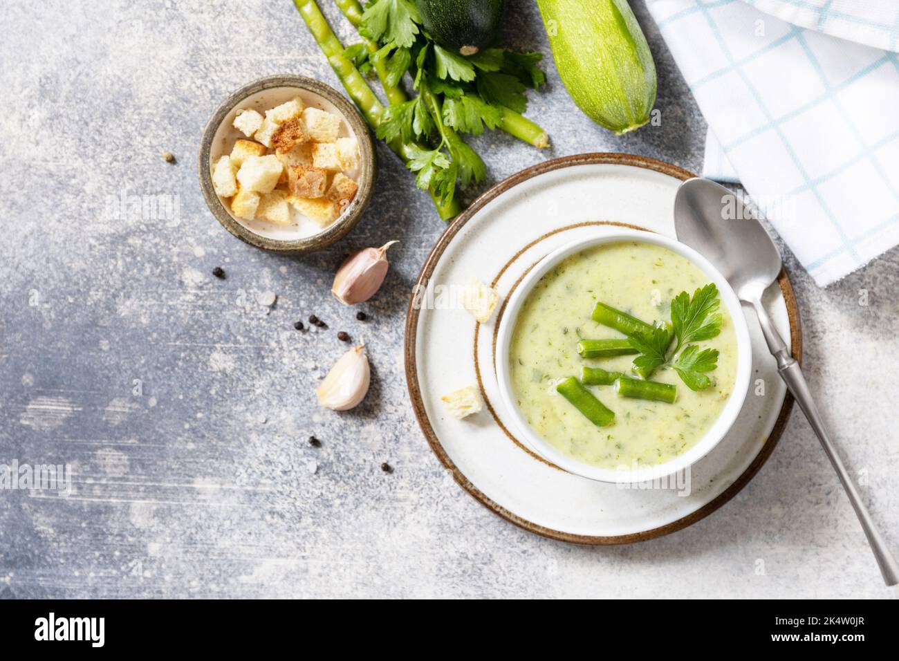 Purea di verdure verdi per zuppa vegana. Cibo sano. Ciotola di fagiolo verde e zuccini crema su un tavolo di pietra. Vista dall'alto. Spazio di copia. Foto Stock