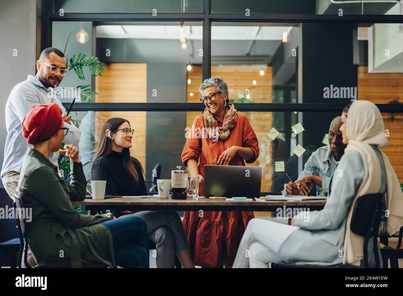 Allegro businesspeople sorridente felicemente durante una riunione in un ufficio creativo. Gruppo di professionisti aziendali di successo che lavorano come team in un multi Foto Stock