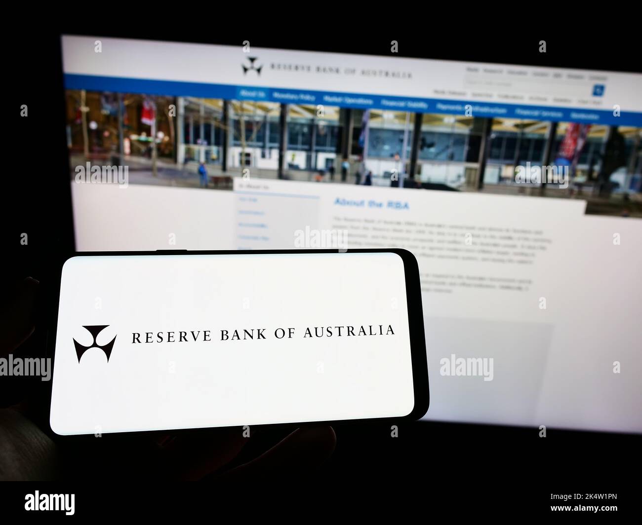 Persona che detiene un telefono cellulare con il logo dell'emittente Reserve Bank of Australia (RBA) sullo schermo di fronte alla pagina web. Messa a fuoco sul display del telefono. Foto Stock