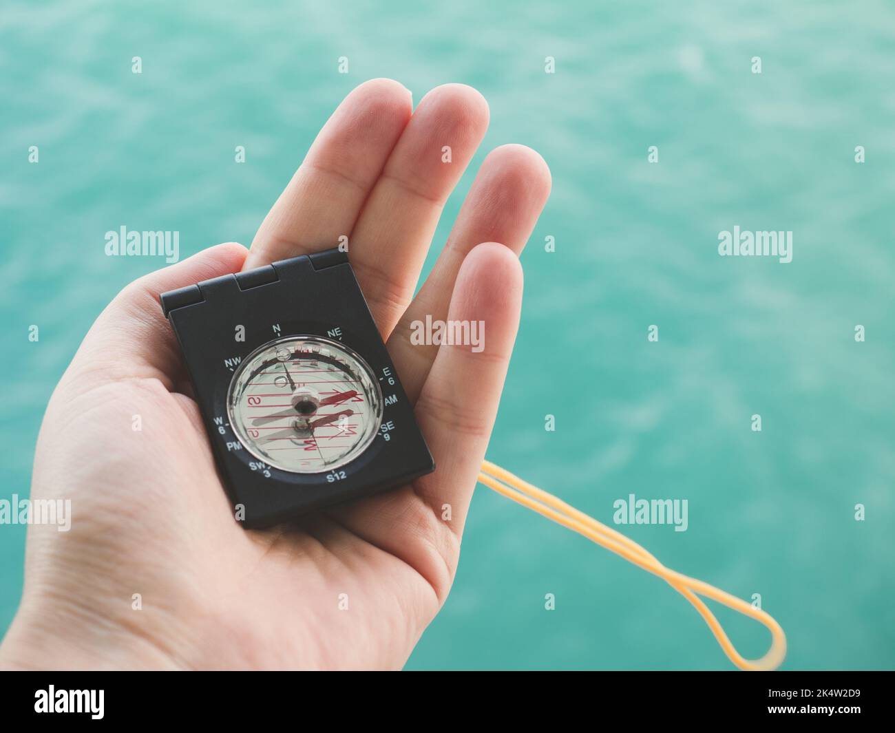 Mano e bussola della donna sullo sfondo delle onde del mare. Vista dall'alto, primo piano. Concetto di vacanza e di viaggio Foto Stock
