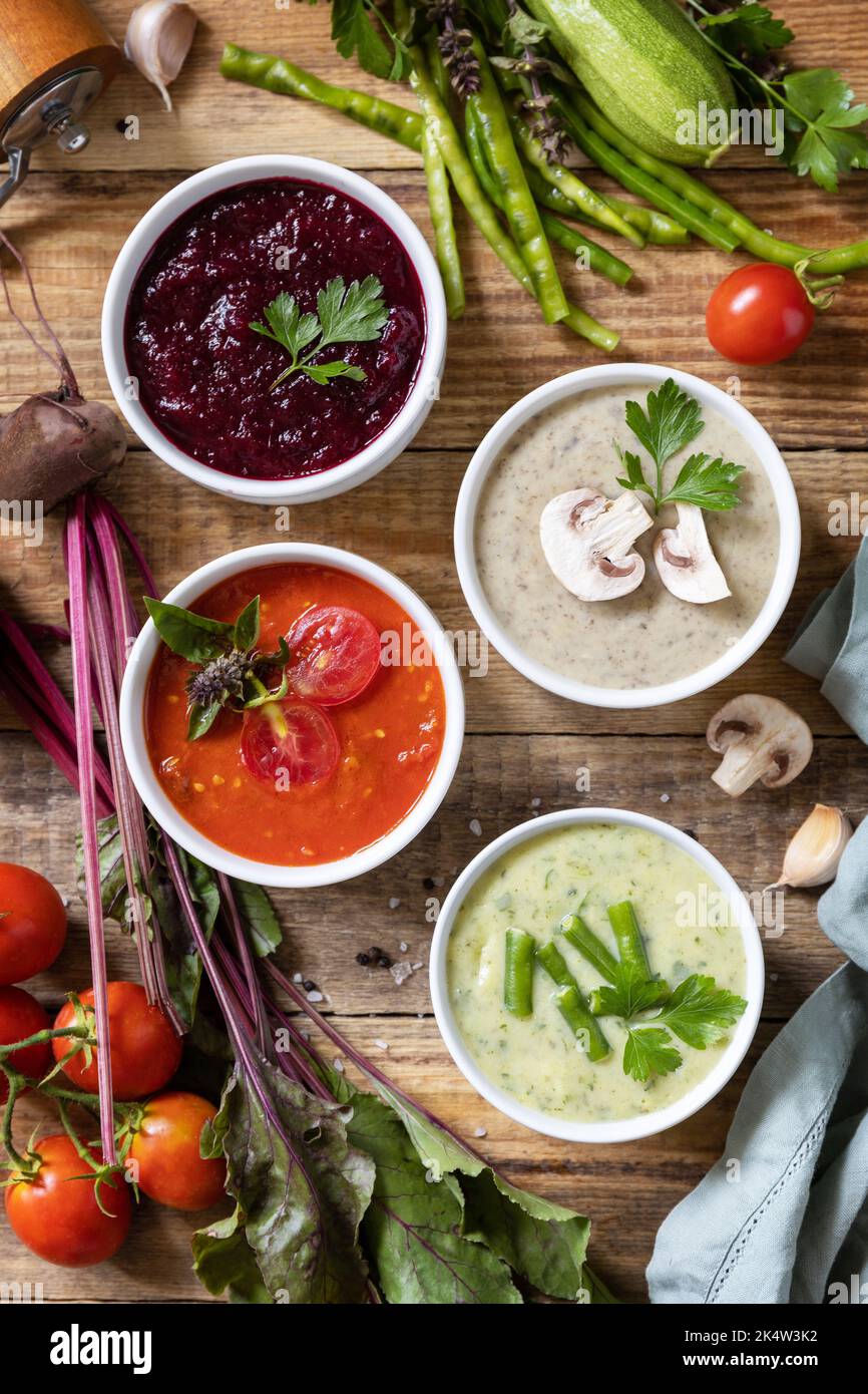 Set autunnale di diverse zuppe di verdure. Cibo sano. Zuppe di panna vegana (pomodori, funghi, barbabietole, fagiolini) su un tavolo di legno rustico. Visualizza fr Foto Stock