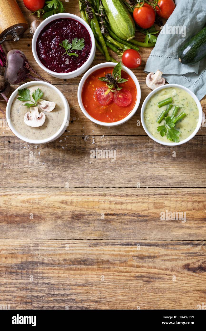 Cibo sano. Set autunnale di diverse zuppe di verdure. Zuppe di panna vegana (pomodori, funghi, barbabietole, fagiolini) su un tavolo di legno rustico. Visualizza fr Foto Stock
