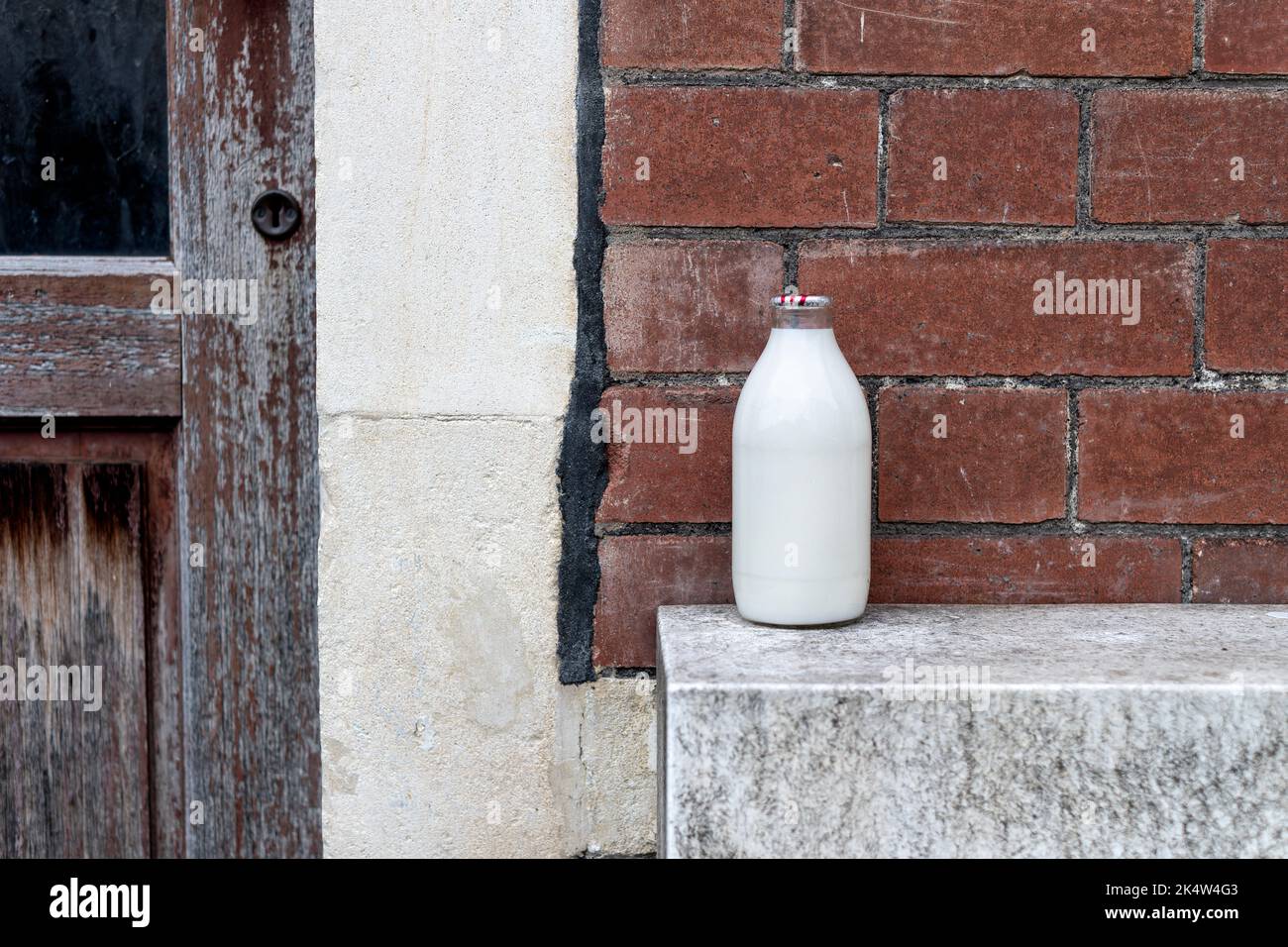 Una pinta piena di latte fresco, in una bottiglia di vetro, lasciata all'esterno di una casa dal milkman locale. Il biberon è sormontato da un foglio di alluminio sicuro Foto Stock