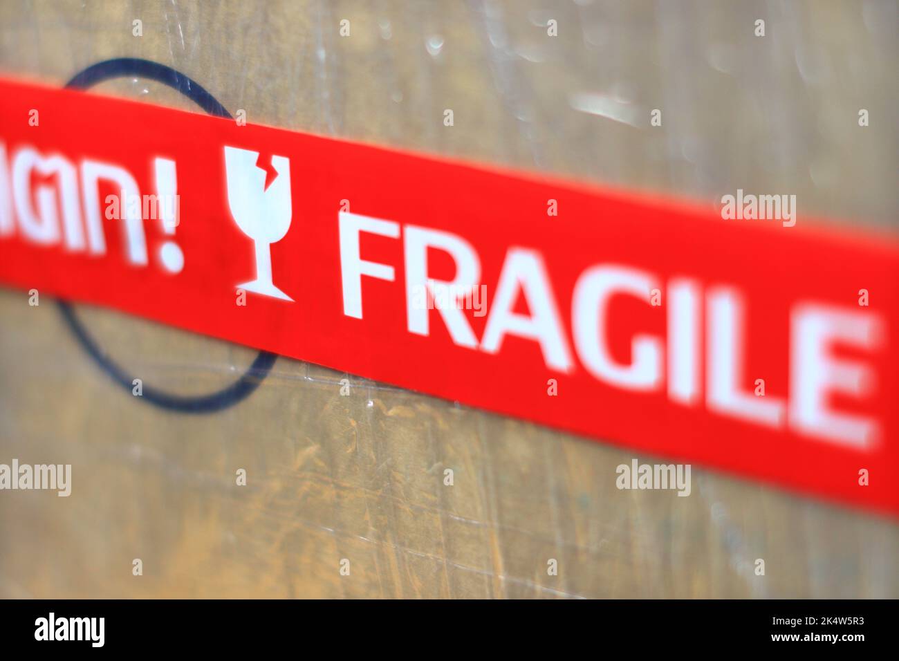 Modello sfocato primo piano adesivo rosso fragile su un pacco con messa a fuoco poco profonda. Foto Stock