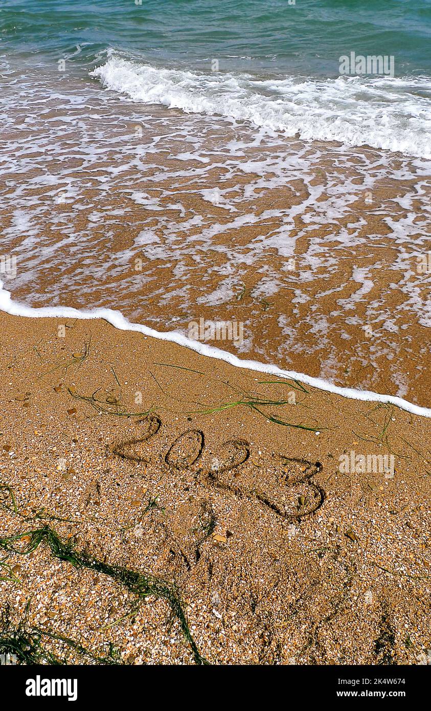 2023 scritto sulla spiaggia. Onde di mare verde turchese con schiuma. Concetto turistico per le vacanze di Capodanno. Struttura naturale. Modello poster Foto Stock
