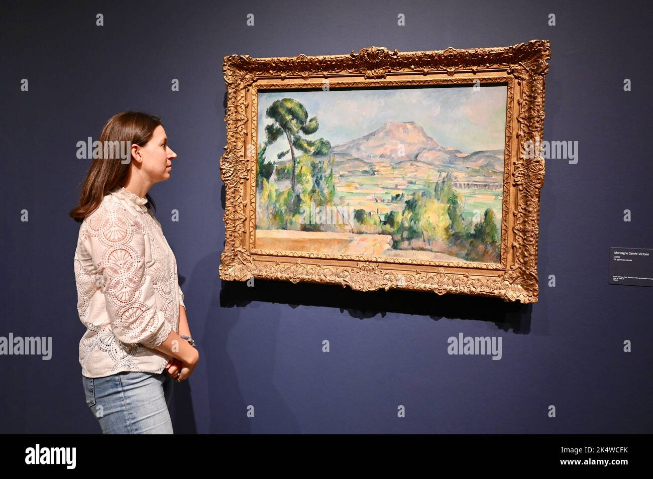 Un dipendente della galleria vede 'Montagne Sainte-Victoire' c1890. Cezanne. The EY Exhibition, Tate Modern, Bankside, Londra. REGNO UNITO Foto Stock