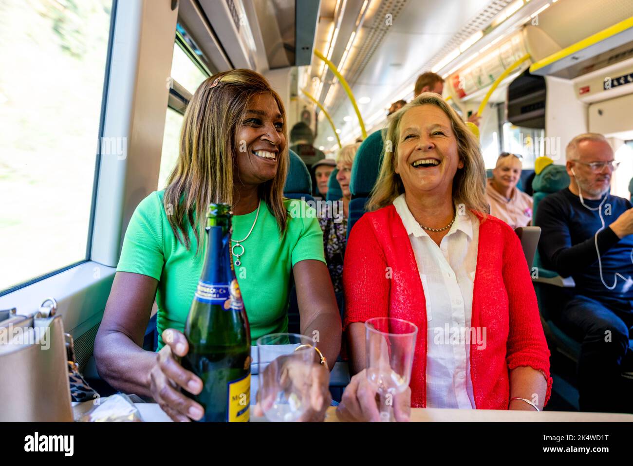Due donne mature godono Di Un bicchiere di Prosecco sul treno, Sussex, Regno Unito. Foto Stock