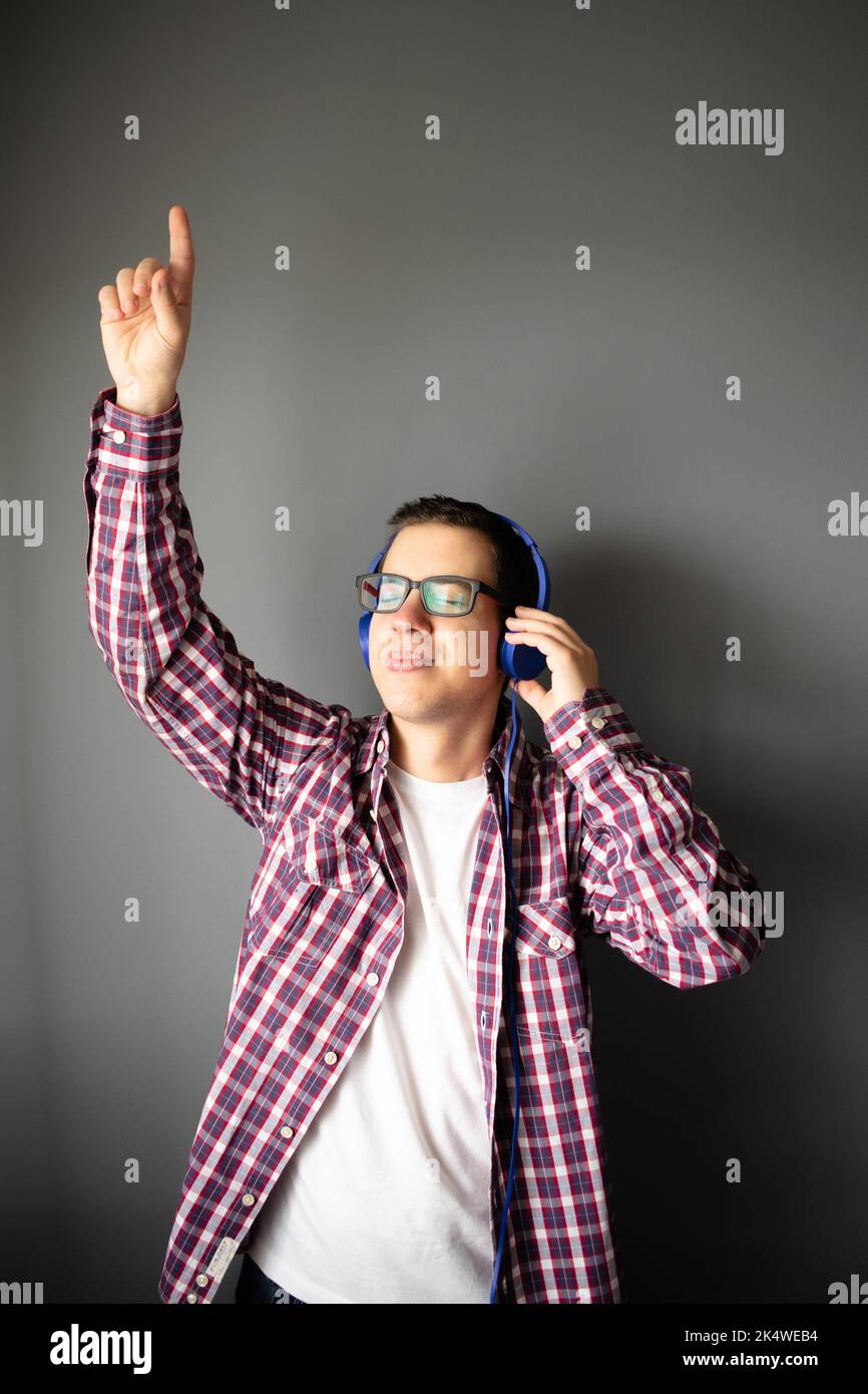 Ritratto di un uomo medio adulto che indossa le cuffie per ascoltare la musica con il braccio in aria Foto Stock
