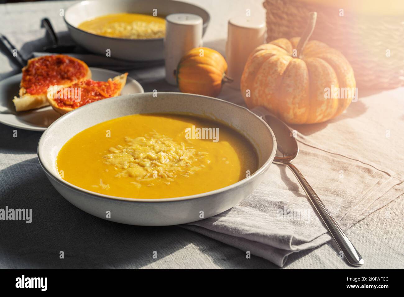 Ciotola di zuppa di zucca cremosa fatta in casa con formaggio e pane con pepe rosso Foto Stock