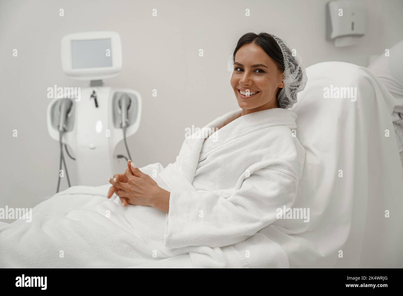 Bella donna in accappatoio bianco durante la procedura medica in clinica di bellezza Foto Stock