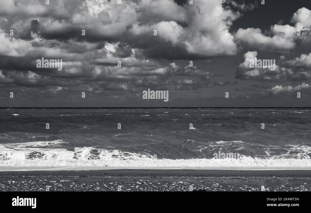 Vista panoramica della spiaggia vuota con acque costiere sotto il cielo nuvoloso, foto monocromatica naturale scattata sulla costa del Mar Nero in una giornata di tempesta, la Crimea Foto Stock