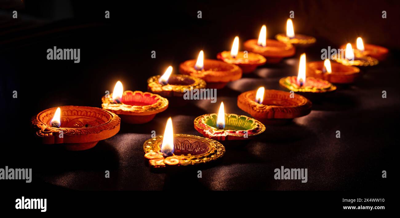 Diwali. Deepavali Hindu festival di luci. Candele di argilla diya in file. Spia dell'olio accesa su sfondo scuro Foto Stock