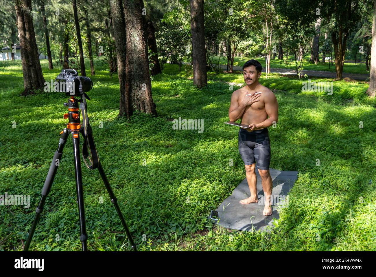 Attivi bei yoga maschile passeggiate in un parco passeggiando foresta prima o dopo un allenamento. Classe di yoga giovane uomo atletico ispanico con tappetino fitness Foto Stock