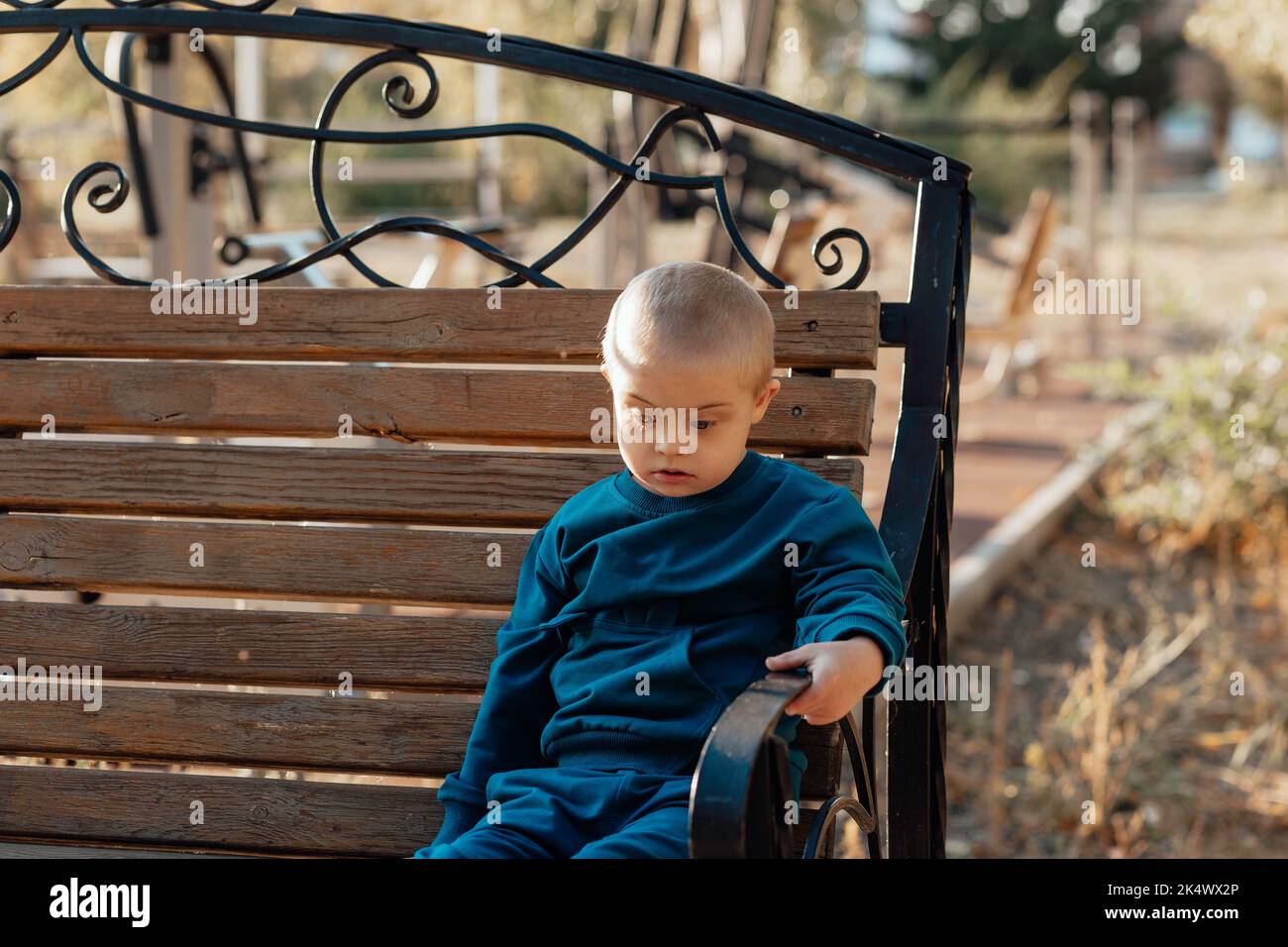 Carino ragazzo biondo con sindrome di Down passeggiate nel parco Foto Stock