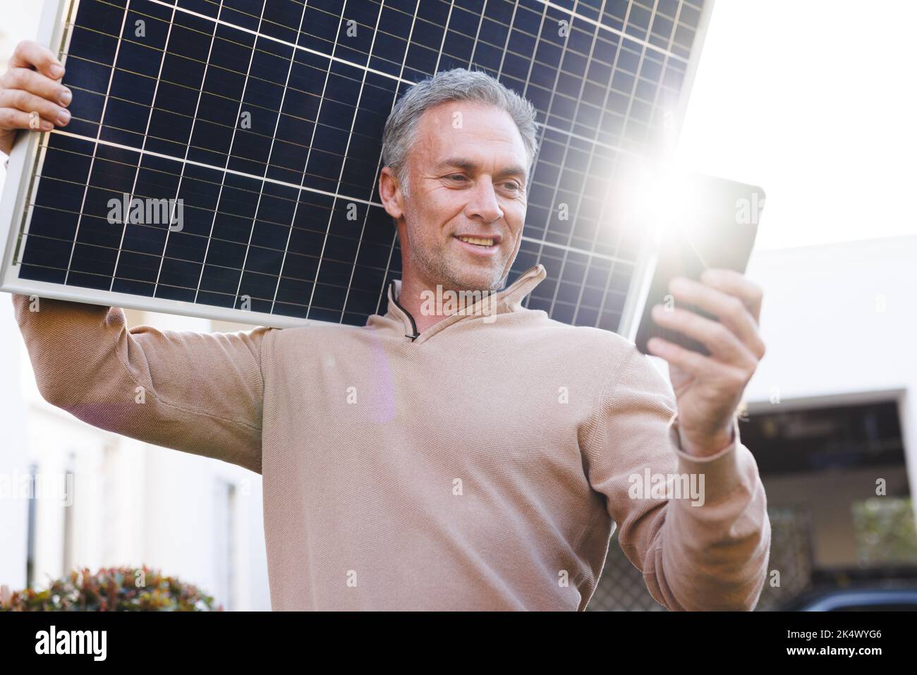 Buon caucasico utilizzando smartphone e golding pannello solare fuori casa Foto Stock