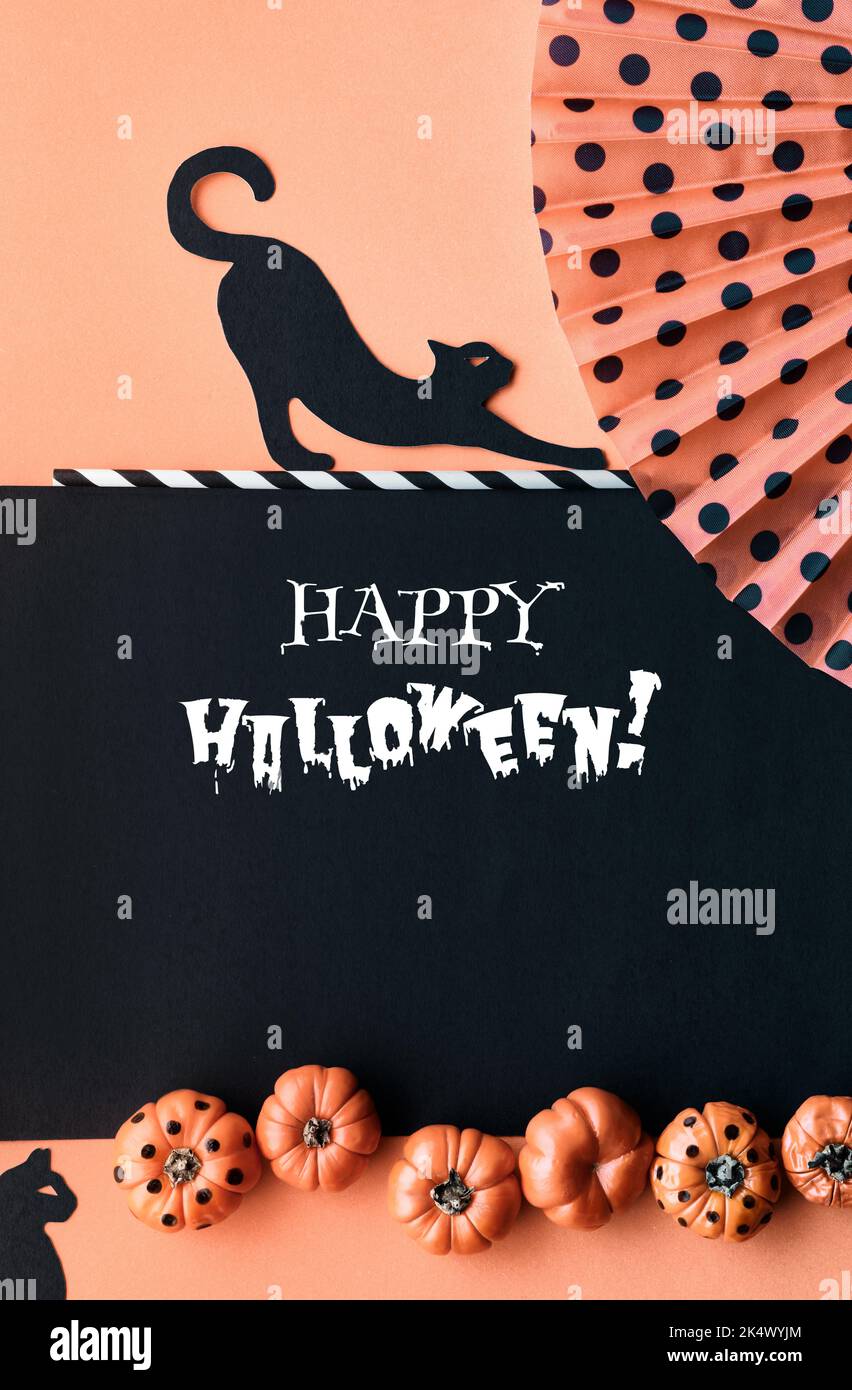 Carino sfondo verticale di Halloween, modello per le storie dei social media. Gatti neri, zucche dipinte in deco e ventilatore con puntini di polka. Arancione nero Foto Stock