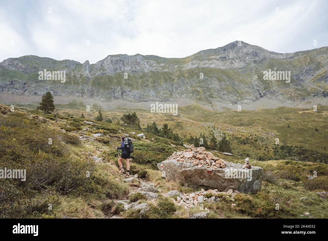 Un escursionista che guarda su una catena montuosa nei Pirenei Foto Stock