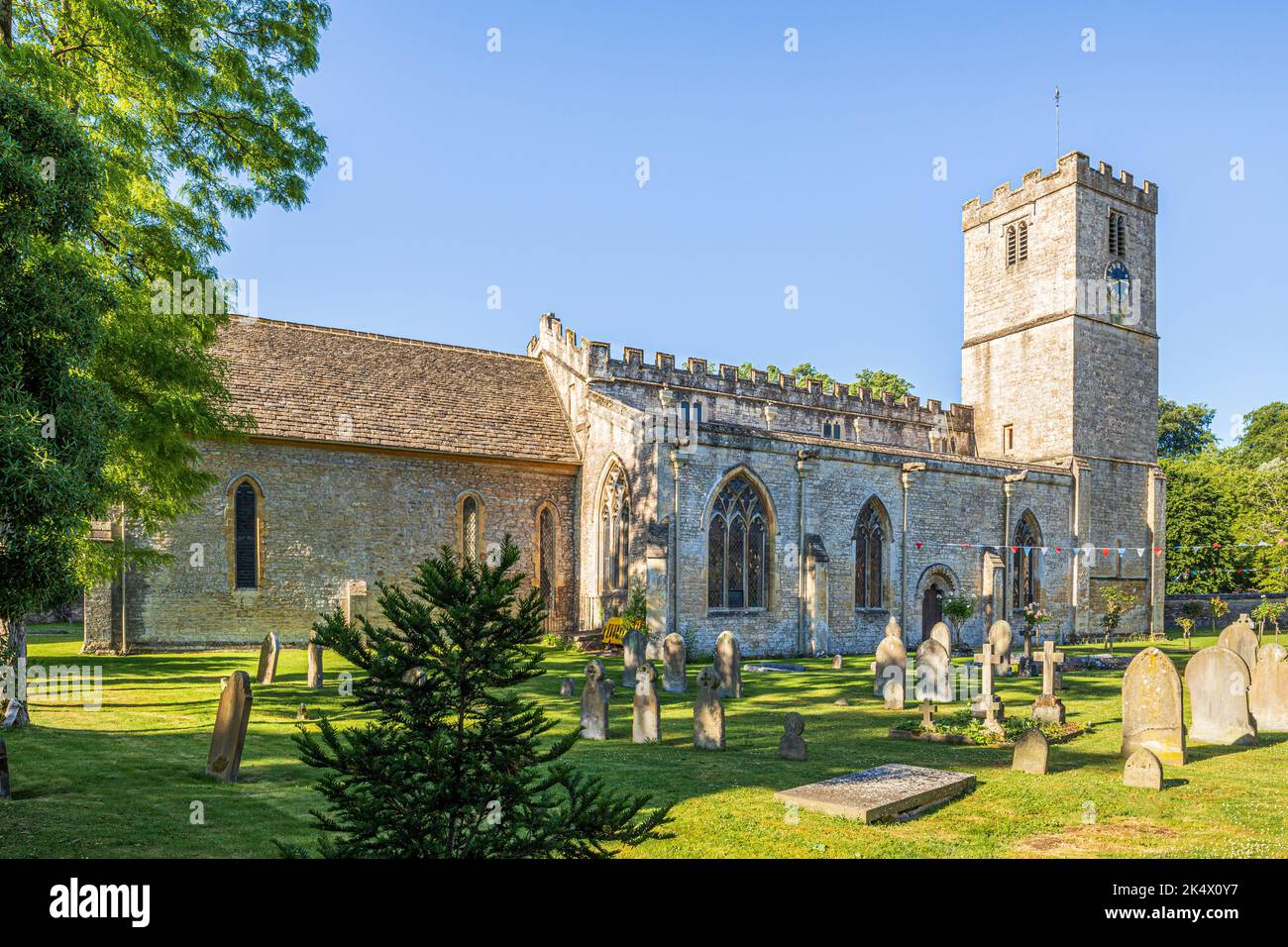 La mattina presto si illuminano a metà estate la chiesa sassone di St Mary nel villaggio Cotswold di Bibury, Gloucestershire, Inghilterra UK Foto Stock