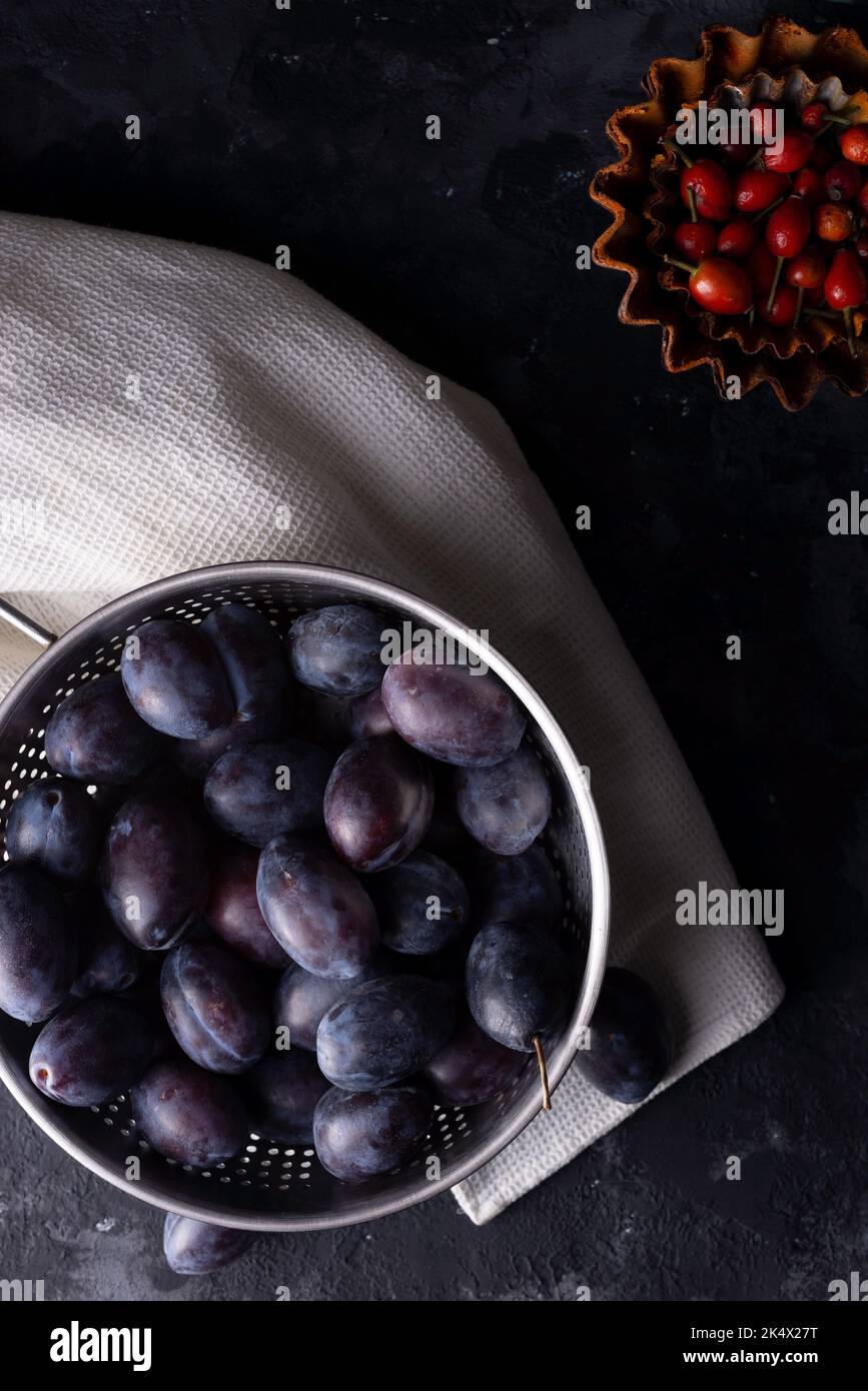 drammatica vita morta autunnale con prugne e zucca su sfondo scuro Foto Stock