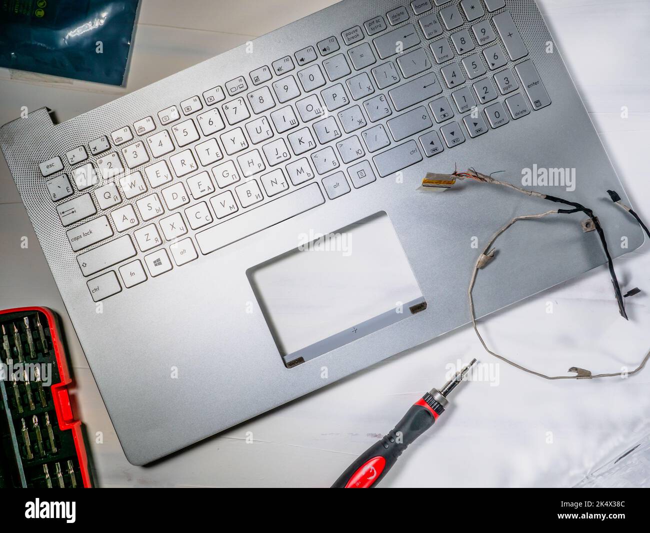 Riparazione e manutenzione del computer portatile, del coperchio del computer portatile smontato e del cacciavite appeso sopra. Foto Stock