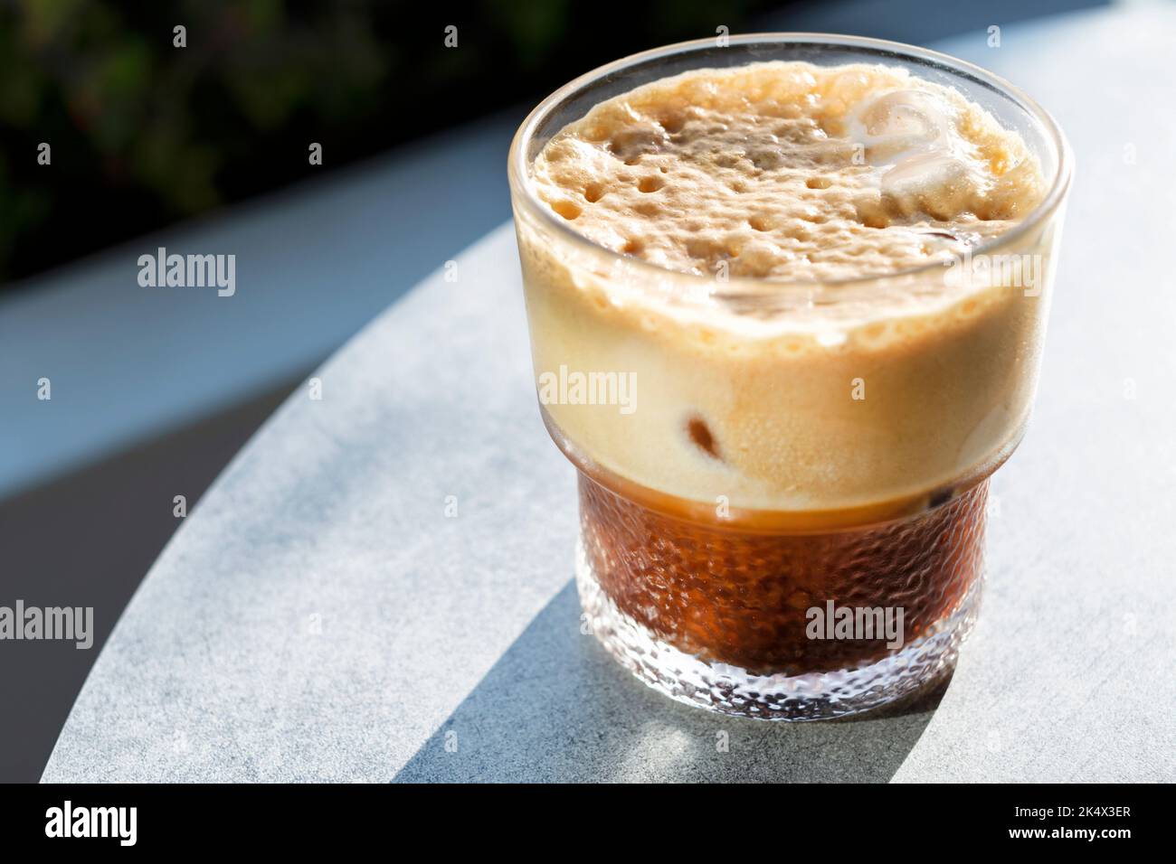 Una bevanda fresca di caffe' ghiacciato o una bevanda servita ad un tavolo fuori da un cafe'. La bevanda ha una crema densa, una bevanda rinfrescante in una giornata calda Foto Stock